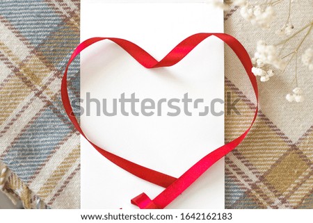 Red ribbon heart awareness on a cozy plaid blanket for World Aids Day concept.