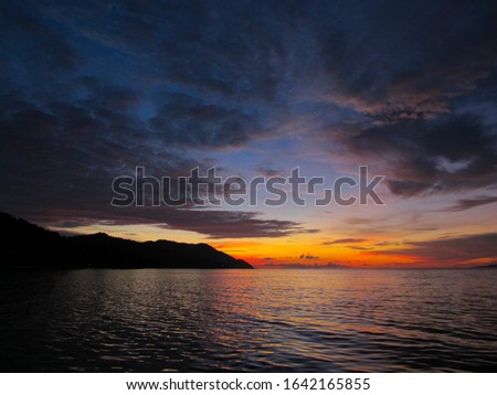 Silhouette of the Kri island on the sunset reflected on the sea