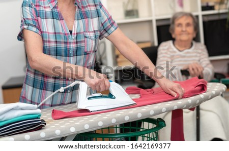 Home helper ironing clothes for elderly woman Royalty-Free Stock Photo #1642169377