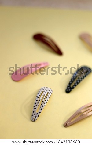 Colorful trendy hair clips on bright yellow background. Selective focus.