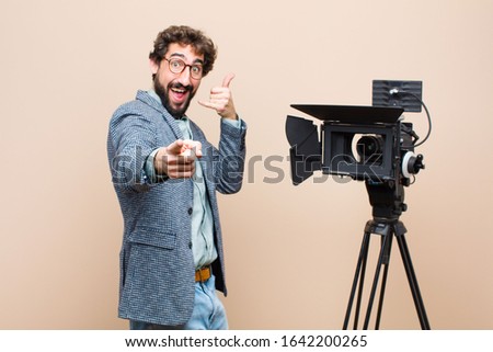 television presenter smiling cheerfully and pointing to camera while making a call you later gesture, talking on phone