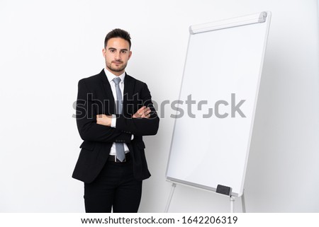 Young man with arms crossed while giving a presentation on white board