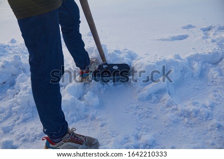 man cleans snow in winter with a shovel