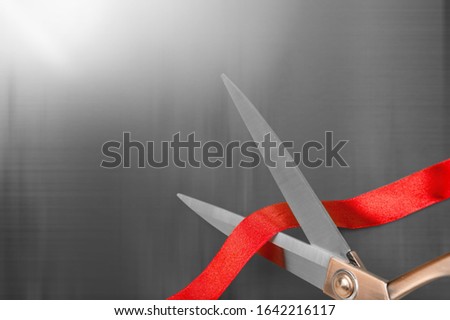 Gold scissors cutting the red silk ribbon