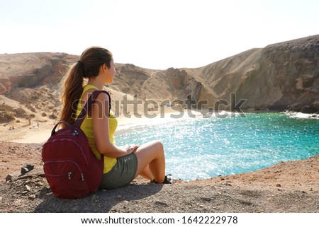 Beautiful young backpacker admiring Playa Papagayo beach in Lanzarote, Canary Islands, Spain