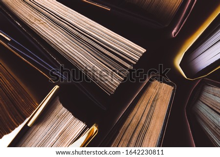 Old and used hardback books or text books seen from above. Books and reading are essential for self improvement, gaining knowledge and success in our careers, business and personal lives