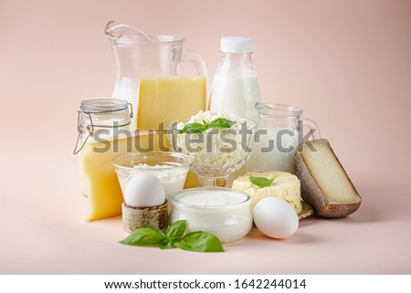 Fresh dairy products, milk, cottage cheese, eggs, yogurt, sour cream and butter on pink background