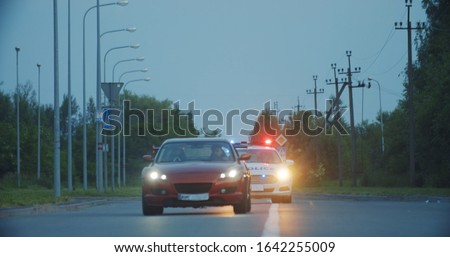 View of self-willed young man driving on modern sports car from the police. Police officer cop chasing a thief driving a patrol car on the highway at daytime. Police in pursuit. Royalty-Free Stock Photo #1642255009