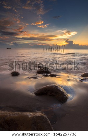 Long Exposure wave with stone and Dramatic Sunset Background