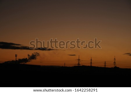 Electricity pylons in the sky and landscape at sunset