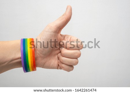 A finger up hand wearing lgbt rainbow gay pride bracelet.