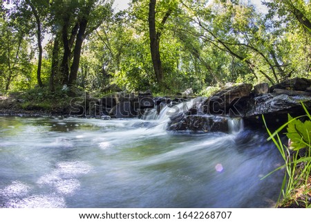 River. Stream in the forest. Long exposure, water blurred in the photo. Moss on stones near the water
