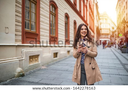 Street life. Business woman with phone on the street. Beautiful young woman with smart phone outdoors at sinlight. Beautiful city girl with smart phone. 