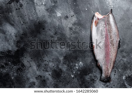 Fresh whole trout fishes. Black background. Top view. Copy space
