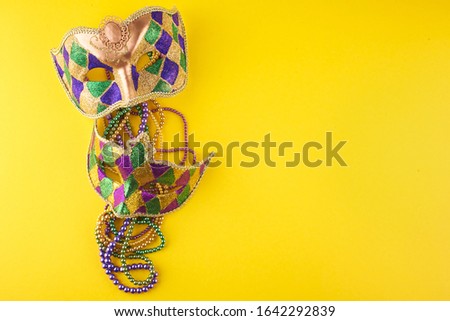 A festive, colorful mardi gras or carnivale mask on a yellow background. Venetian masks.