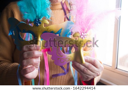 woman with colorful mask on her hands, party and celebration concept