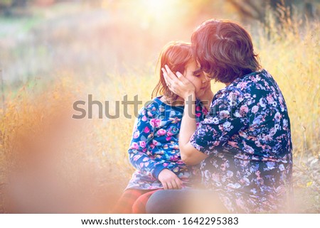 Happy family. Pregnant mom and little daughter hugging and kissing at sunset in autumn in forest. Laughter, happiness and fun together