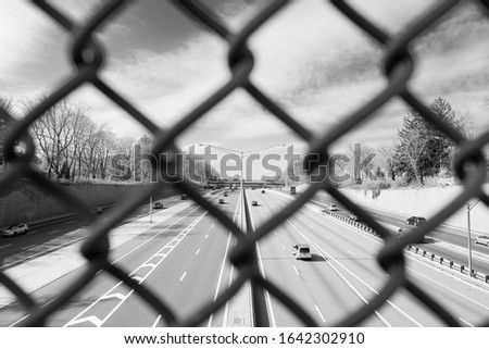 Industrial isolated highway streetlamp. Looking through chain link fence over highway. 
