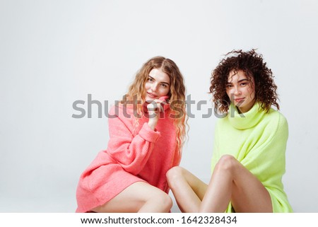 Portrait of two beautiful women in soft comfort sweaters against white background