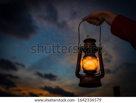 
A woman's hand holds a lantern.  Idea and creativity. The background is a beautiful sunset Royalty-Free Stock Photo #1642336579