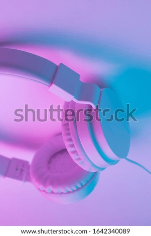 Retro 90s style photo of white  modern stylish headphone in neon lights. Music concept