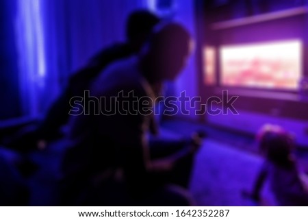 father and children watching together tv in a dark room, family, television, leisure, cinema, blurred image