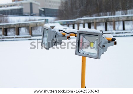 Led spotlight on yellow stand on winter urban background. Stock photo for web and print with empty space for text.