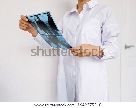 Doctor woman in medical uniform examines an x-ray, diagnosis of the disease.