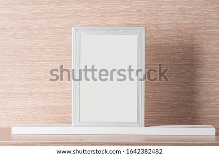 Light gray photo frame on a light wooden background , place for text