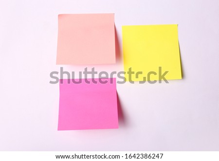 Square sticky sticks of different colors on a pink background. Quick notes paper as a template for design.