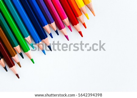 bright multi-colored flat lay pencils for drawing on a white background, place for text