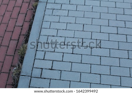 Concrete pavers of red and gray. Sidewalk of gray and pink pavers, blurred background.