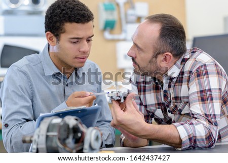 two men repairing electronic device