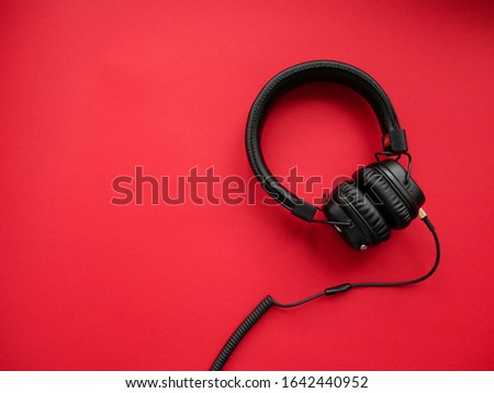 Classic black wired headphones on colored paper background. Retro style. 80s. Pop culture. Top view. Minimal Music Concept