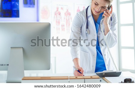 Serious doctor on the phone in her office Royalty-Free Stock Photo #1642480009