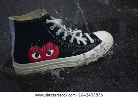 Comme des Garçons Converse Splashing In Water Puddle Royalty-Free Stock Photo #1642493836