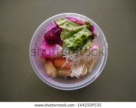Fruit Salad in plastic cup with ingredient fresh raw fruit such as dragon fruit, apple, melon, pear, papayas, lettuce vegetables topping mayonnaise and grated cheese 