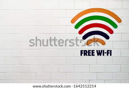 Colorful free Wifi zone sign or symbol on white brick wall with copy space.