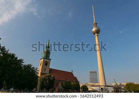 TV tower and St.Marien Church at the city of Berlin, Capital City of Germany. Fernsehturm und St. Marienkirche at Alexanderplatz before  Sunset. The top of the tower become golden from the falling sun