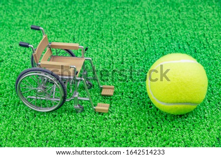 Hard tennis ball, wheelchair and artificial grass (wheelchair tennis image)
