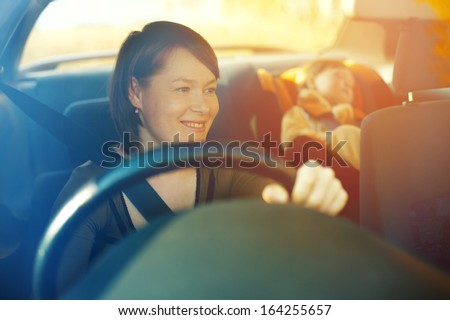 The child in a safety seat near to mother who sits on forward sitting of the car. Royalty-Free Stock Photo #164255657