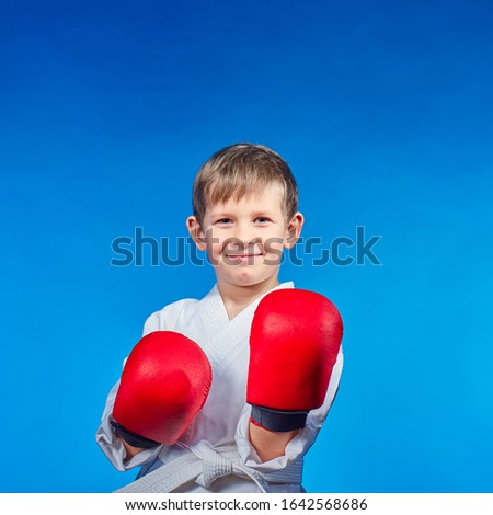 On a blue background, a little cheerful athlete with red overlays on his hands