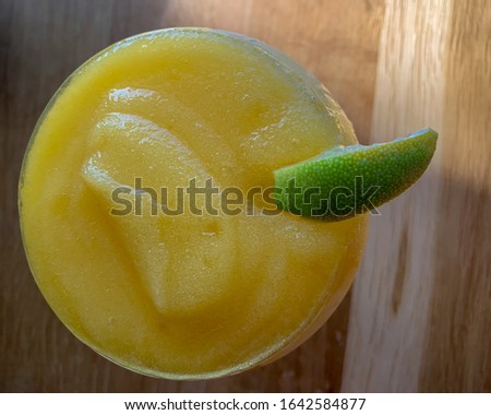 Top view of a frozen mango margarita with a wedge of lime on the rim.