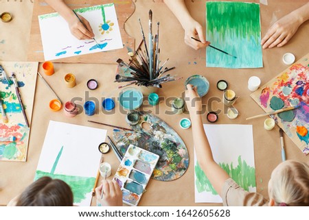 High angle view of group of children painting their pictures with watercolor paints during art lesson