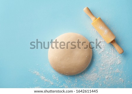 Dough with flour and rolling pin on blue background top view. Bakery concept. Flat lay.