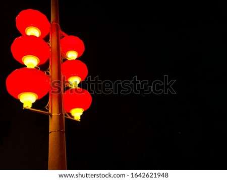Close view of a street lamp with traditional Chinese lanterns isolated on a black background with copy space.