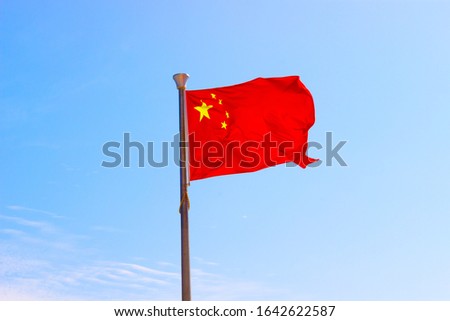 National flag of China or officially the People's Republic of China (PRC) waving in the wind on blue sky background. Selective focus