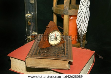 very old books with old thermometer barometer and candle feather pen