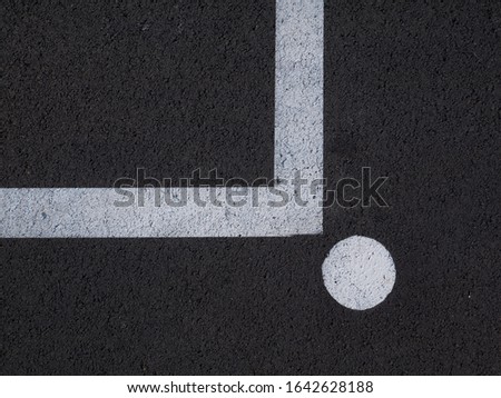 The white line is colored L in the upper left corner. A circle is marked after the line. The substrate is dark asphalt. Part of a training ground for drivers.
