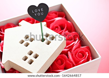 Business, finance, property ladder, mortgage loan, love, gifts or Valentine's day concept : Wood house model with love you tag and red roses on red background with copy space for adding or mock up